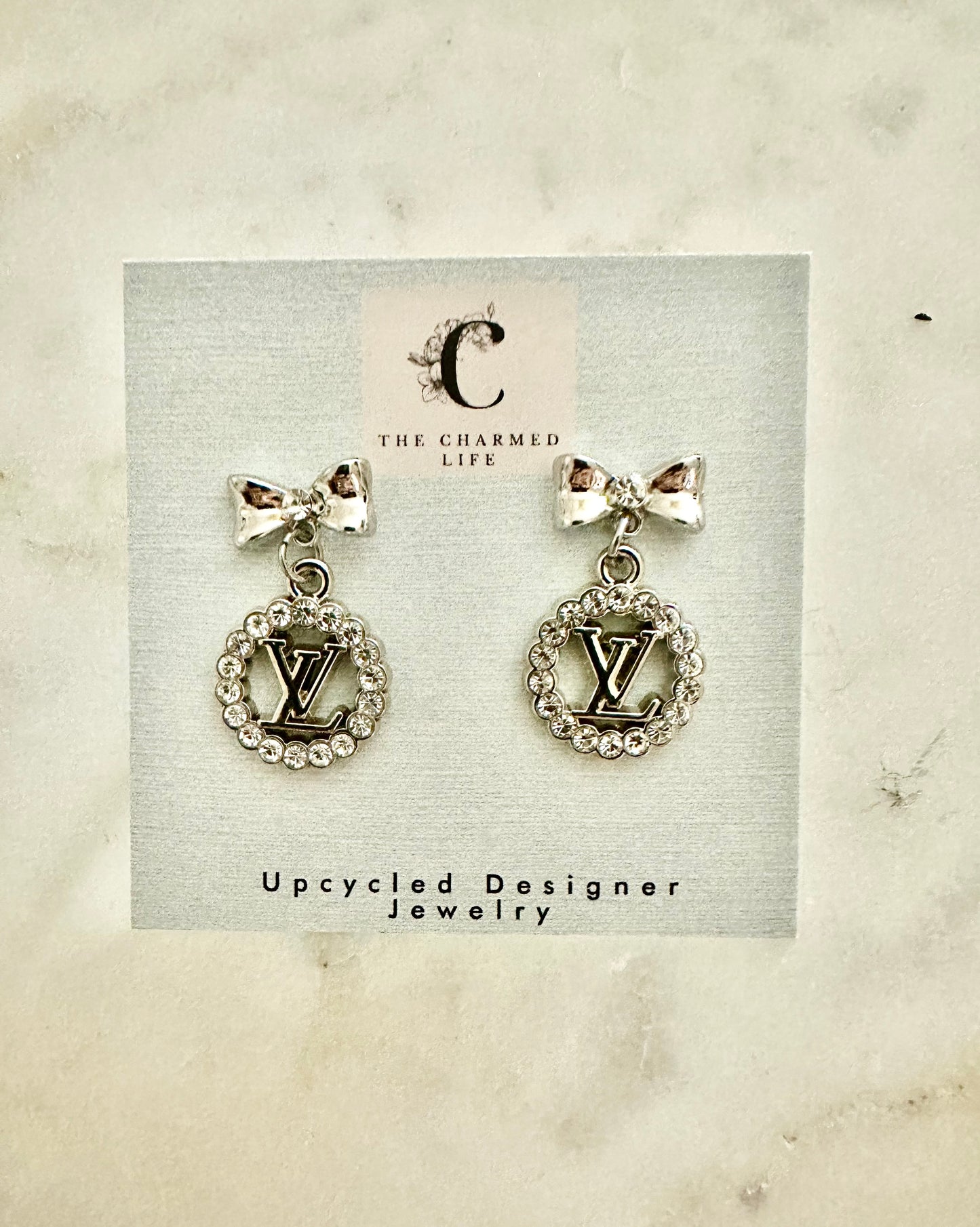 LV silver tone round bow and rhinestone earrings